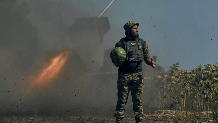 A Ukrainian soldier holds a watermelon and thumbs up as a rocket launch system fires in the font line in Donetsk region, eastern Ukraine, Saturday, Aug. 3, 2022.   -   Copyright  Kostiantyn Liberov