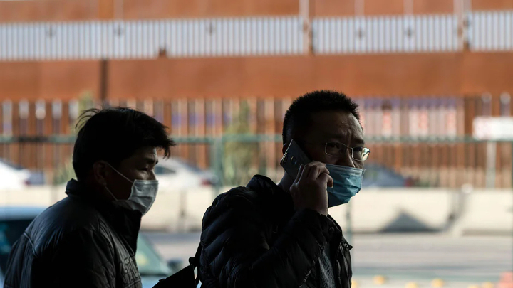 Two Chinese people wearing masks on their way to officeAFP file photo