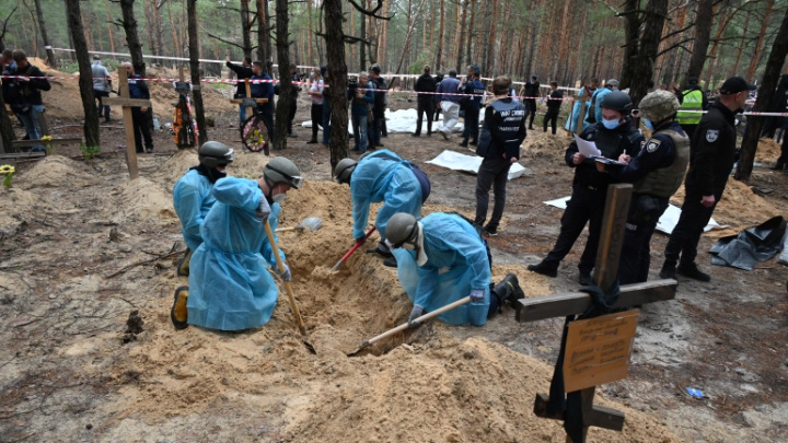 Forensic technicians dig a grave in a forest on the outskirts of Izyum, eastern Ukraine [Sergey Bobok/AFP]