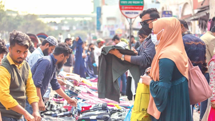 The sale of warm clothes at makeshift shops in the capital has gained momentum with the bone-chilling cold gripping the country amid a fall in temperature. The photo was taken from a footpath in front of New Market on Tuesday. – SUN PHOTO