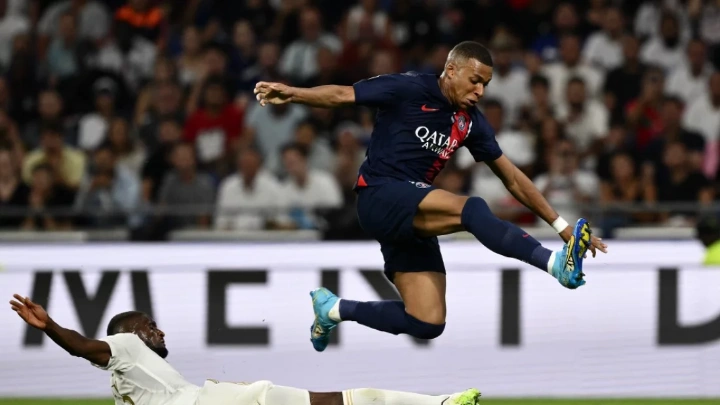 Paris Saint-Germain's Kylian Mbappe avoids the tackle of Lyon's Angolan Belgian during Sunday’s Ligue 1 match in Decines-Charpieu Photo: AFP
