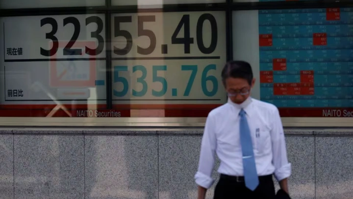 A man stands in front of an electric board displaying the Nikkei stock average outside a brokerage in Tokyo, Japan, July 28, 2023. REUTERS/Kim Kyung-Hoon/File Photo