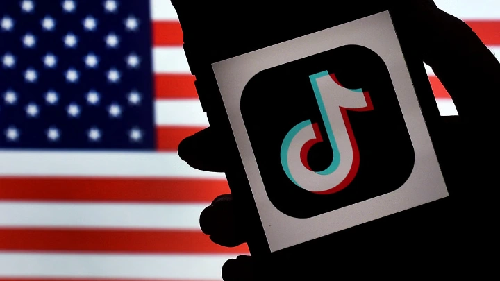 In this photo illustration, the social media application logo, TikTok is displayed on the screen of an iPhone on an US flag background on August 3, 2020 in Arlington, Virginia. Photo: AFP