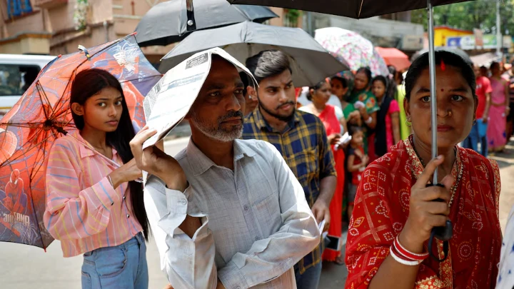 A man uses a newspaper as others use umbrellas to protect themselves from the heat as they wait to vote outside a polling station during the fifth phase of India’s general election in Howrah district of the eastern state of West Bengal, India, May 20, 2024. REUTERS/Sahiba Chawdhary