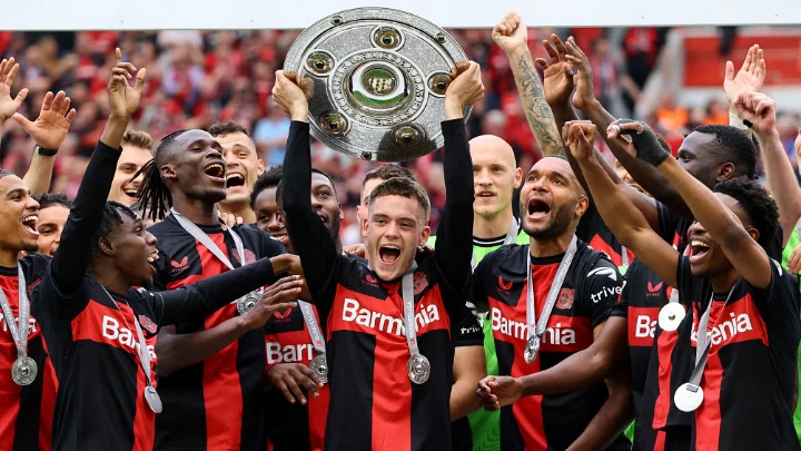 Bayer Leverkusen's Florian Wirtz celebrates with the trophy and teammates after winning the Bundesliga and going unbeaten. Photo: Reuters